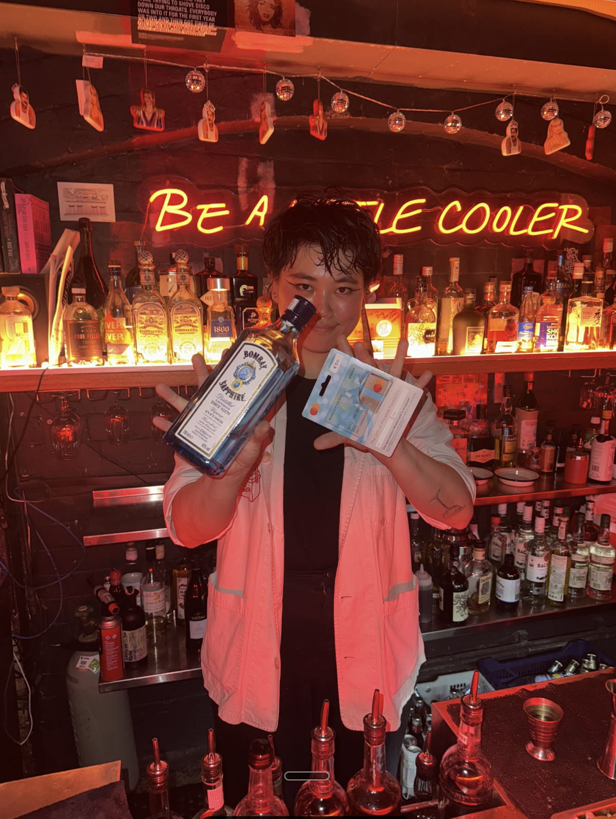 Bartender holding a bottle of gin behind a bar